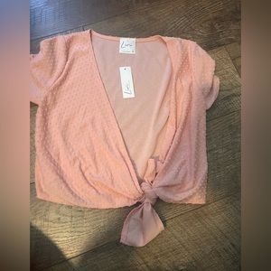 still has tags. pink cropped shirt that ties in the front.